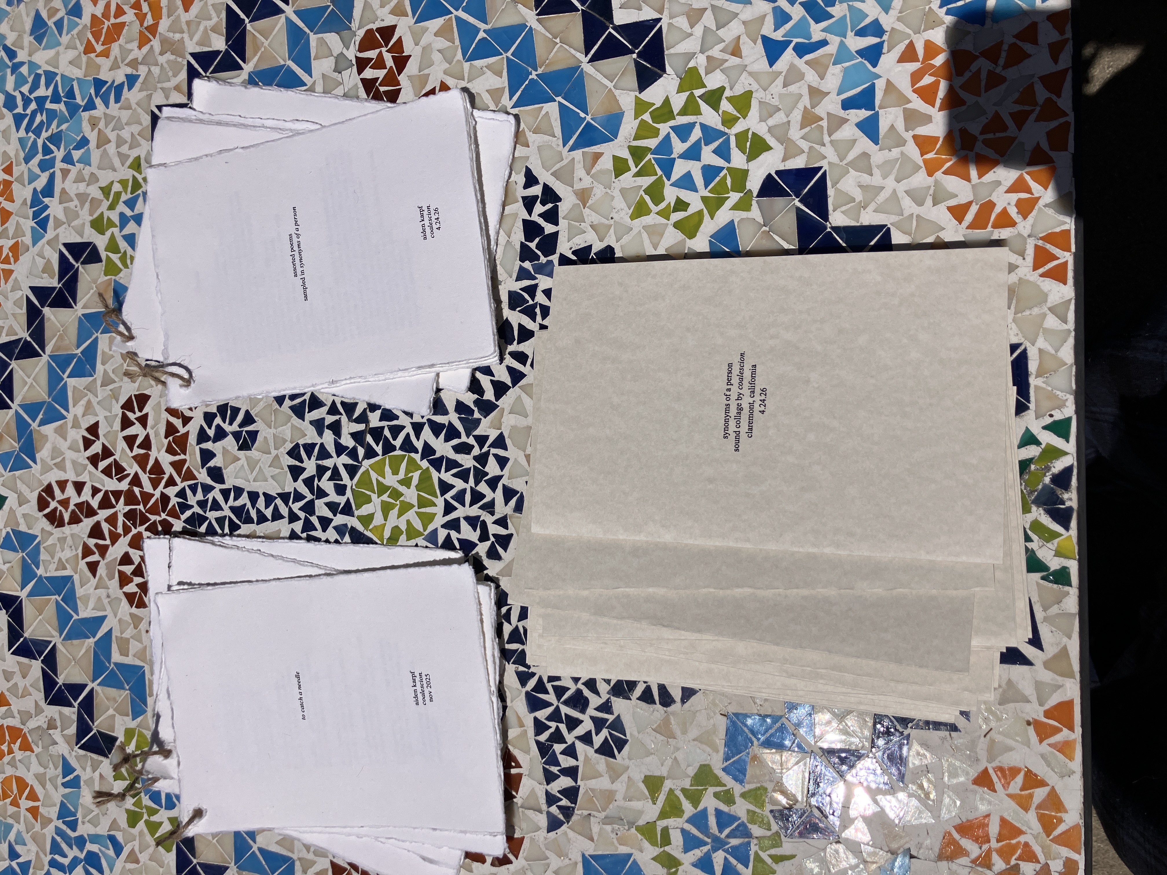 Handmade poetry booklets and Synonyms of a Person programs arranged on a mosaic table